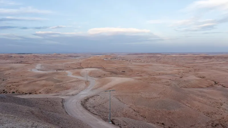 Winding tracks in the Agafay stone desert, arid hills and the Atlas range on the horizon