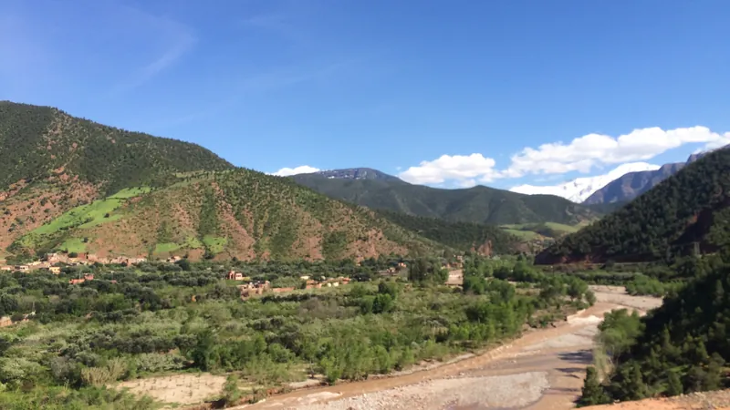 Ourika valley: a river with a pebbly bed, green orchards and High Atlas mountains